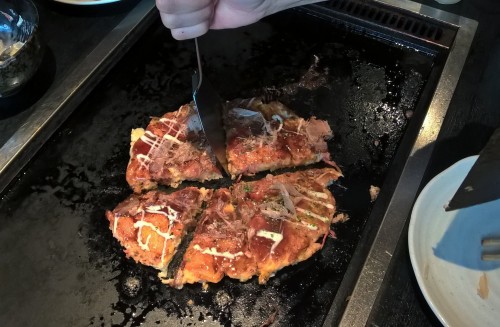 Photo d'un okonomiyaki, spécialité culinaire japonaise, sur sa plaque chauffante.