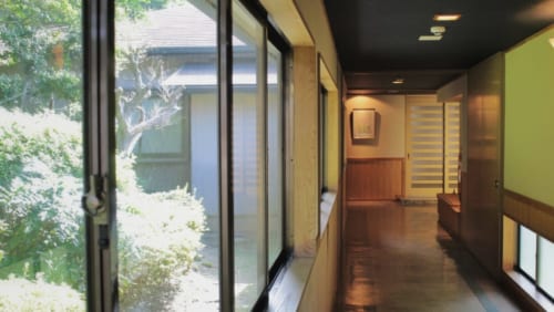 Un couloir du ryokan Satsuki Bessou de Tamana, dont les grandes baies vitrées donnent sur un jardin