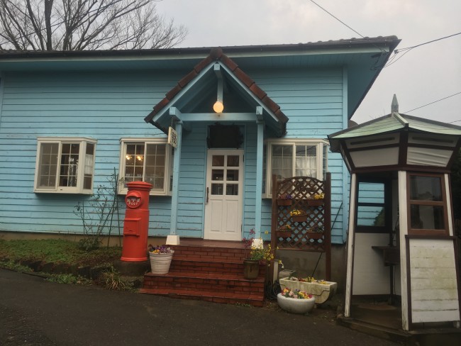 A quant little blue building with a white door in Nokonoshima