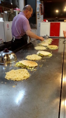 Juju Okonomiyaki restaurant where Okonomiyaki is being grilled.