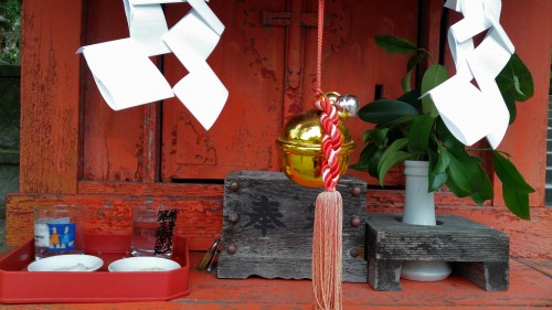 Close up of a little shrine with a bell hanging down at Toyotama shrine in Kagoshima.