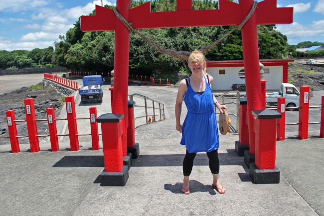 Person at the torii gate with the lid on her head at Kamafuta Jinja in Kagoshima.